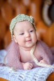 Lyckligt nyfött behandla som ett barn lögner på en stol i en härlig stucken hatt, med intresse ser omkring, joyfully leenden royaltyfri foto Lyckligt nyfött behandla som ett barn lögner på en stol i en härlig stucken hatt, med intresse ser omkring, joyfully leenden royaltyfri foto