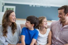 Lächelnde Familie, die auf Sofa im Wohnzimmer sitzt Lizenzfreies Stockfoto Lächelnde Familie, die auf Sofa im Wohnzimmer sitzt Lizenzfreies Stockfoto