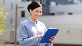 Lächelnde Geschäftsfrau mit Tabletten-PC in der Stadt stock footage Lächelnde Geschäftsfrau mit Tabletten-PC in der Stadt stock footage