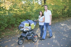 Lächelnde Paare mit Kinderwagen in einem Park Stockbild Lächelnde Paare mit Kinderwagen in einem Park Stockbild