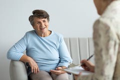 Lächelnde ältere Frau, die mit einem Psychologen über glückliches Leben spricht stockfotografie Lächelnde ältere Frau, die mit einem Psychologen über glückliches Leben spricht stockfotografie