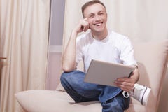 Lächelnder hübscher kaukasischer Mann mit Tablet-Computer auf Couch Stockbilder Lächelnder hübscher kaukasischer Mann mit Tablet-Computer auf Couch Stockbilder