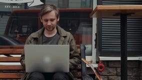 Lächelndes kaukasisches Mannneuschreiben im Sozialen Netz mit seinem Freund über Laptop-Computer beim Stillstehen im Bäckereispei stock video footage Lächelndes kaukasisches Mannneuschreiben im Sozialen Netz mit seinem Freund über Laptop-Computer beim Stillstehen im Bäckereispei stock video footage