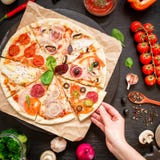 Läcker pizza med ingredienser och kvinnahanden på den mörka tabellen Lekmanna- lägenhet Top beskådar italienska matlagningmatingr fotografering för bildbyråer Läcker pizza med ingredienser och kvinnahanden på den mörka tabellen Lekmanna- lägenhet Top beskådar italienska matlagningmatingr fotografering för bildbyråer