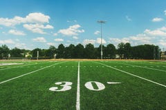 Línea de yardas 30 en campo de fútbol americano y el cielo azul imagenes de archivo Línea de yardas 30 en campo de fútbol americano y el cielo azul imagenes de archivo