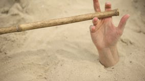 Mão afundando na areia movediça tentando tirar dicas para sobreviver no  deserto enterrado