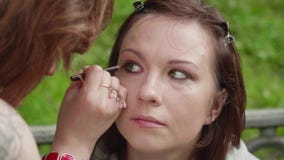 Maak omhoog kunstenaar toepast rokerige ogenmake-up op meisjes` s gezicht vóór photoshoot stock video Maak omhoog kunstenaar toepast rokerige ogenmake-up op meisjes` s gezicht vóór photoshoot stock video