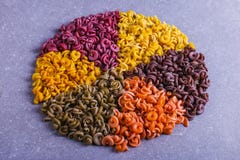 Macarrão colorido da forma incomum com as tinturas vegetais naturais, alinhado em um círculo close up do fundo foto de stock Macarrão colorido da forma incomum com as tinturas vegetais naturais, alinhado em um círculo close up do fundo foto de stock