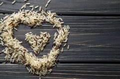 Macro, cierre para arriba Colina en forma de corazón del arroz salvaje en un fondo de madera oscuro Cocina asiática fotos de archivo libres de regalías Macro, cierre para arriba Colina en forma de corazón del arroz salvaje en un fondo de madera oscuro Cocina asiática fotos de archivo libres de regalías