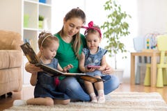 Madre abbastanza giovane che legge un libro alle sue figlie fotografia stock libera da diritti Madre abbastanza giovane che legge un libro alle sue figlie fotografia stock libera da diritti