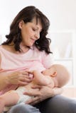 Madre che allatta e che abbraccia il suo bambino all'interno fotografia stock Madre che allatta e che abbraccia il suo bambino all'interno fotografia stock