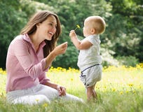 Madre che dà il fiore del bambino nel parco fotografia stock libera da diritti Madre che dà il fiore del bambino nel parco fotografia stock libera da diritti