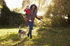 Madre con el niño que toma el perro para el paseo en Autumn Garden fotografía de archivo Madre con el niño que toma el perro para el paseo en Autumn Garden fotografía de archivo