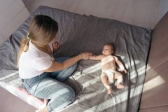 Madre con suo figlio neonato mettere sul letto nei raggi di luce solare fotografia stock libera da diritti Madre con suo figlio neonato mettere sul letto nei raggi di luce solare fotografia stock libera da diritti