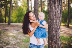 Madre de moda hermosa joven con el pelo moreno largo que detiene a una hija rubia con los ojos azules un a?o de nacimiento en a imagen de archivo libre de regalías Madre de moda hermosa joven con el pelo moreno largo que detiene a una hija rubia con los ojos azules un a?o de nacimiento en a imagen de archivo libre de regalías