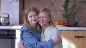 Madre di amore, ritratto della mamma felice con la piccola figlia che abbraccia e baci sulla guancia in cucina a casa archivi video Madre di amore, ritratto della mamma felice con la piccola figlia che abbraccia e baci sulla guancia in cucina a casa archivi video
