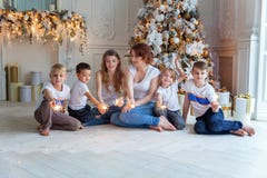 Madre e cinque bambini che giocano stella filante vicino all'albero di Natale a casa fotografia stock libera da diritti Madre e cinque bambini che giocano stella filante vicino all'albero di Natale a casa fotografia stock libera da diritti