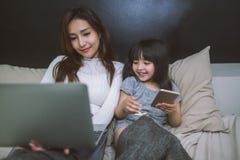 Madre e hija que usa smartphone y el ordenador portátil junto en dormitorio Concepto de la tecnología imágenes de archivo libres de regalías Madre e hija que usa smartphone y el ordenador portátil junto en dormitorio Concepto de la tecnología imágenes de archivo libres de regalías