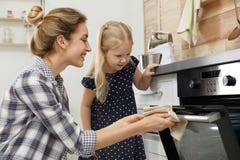 Madre ed il suo alimento bollente della figlia in forno fotografia stock Madre ed il suo alimento bollente della figlia in forno fotografia stock