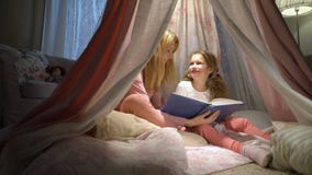 Madre felice della famiglia e sua piccola la figlia che leggono un libro in una tenda a casa stock footage Madre felice della famiglia e sua piccola la figlia che leggono un libro in una tenda a casa stock footage