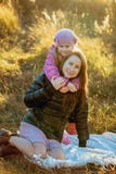 Madre hermosa joven con su hija en un paseo en un día soleado del otoño Se sientan en una tela escocesa en la hierba cerca de uno fotografía de archivo Madre hermosa joven con su hija en un paseo en un día soleado del otoño Se sientan en una tela escocesa en la hierba cerca de uno fotografía de archivo