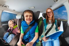Madre joven que viaja en coche con dos niños fotografía de archivo Madre joven que viaja en coche con dos niños fotografía de archivo
