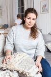 Madre stanca che si siede sul sofà quando il suo daugrter che lava sui piatti sulla cucina fotografie stock libere da diritti Madre stanca che si siede sul sofà quando il suo daugrter che lava sui piatti sulla cucina fotografie stock libere da diritti