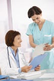 Maestría médica sonriente que trabaja con el ayudante imágenes de archivo libres de regalías Maestría médica sonriente que trabaja con el ayudante imágenes de archivo libres de regalías