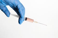 Main dans la seringue bleue de participation de gant avec la gouttelette du vaccin sur à bec photos stock Main dans la seringue bleue de participation de gant avec la gouttelette du vaccin sur à bec photos stock