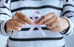 Main de femme tenant le ruban rose du symbole de lutte de cancer du sein photo stock Main de femme tenant le ruban rose du symbole de lutte de cancer du sein photo stock