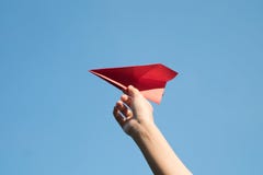 Main de femme tenant une fusée de papier rouge avec un fond bleu lumineux photographie stock libre de droits Main de femme tenant une fusée de papier rouge avec un fond bleu lumineux photographie stock libre de droits