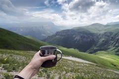 Main femelle avec une tasse de thé sur un fond des montagnes photographie stock libre de droits Main femelle avec une tasse de thé sur un fond des montagnes photographie stock libre de droits