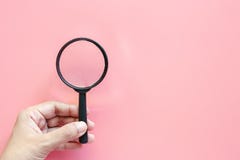 Main tenant une loupe sur le fond rose images stock Main tenant une loupe sur le fond rose images stock