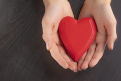 Mains d'un enfant d'adolescent tenant un coeur en bois rouge dans leurs mains images stock Mains d'un enfant d'adolescent tenant un coeur en bois rouge dans leurs mains images stock