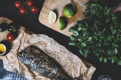 Mains en cours de faire cuire des poissons, poivre, persil, tomate, chaux sur une planche à découper sur une vue supérieure de fo photographie stock libre de droits Mains en cours de faire cuire des poissons, poivre, persil, tomate, chaux sur une planche à découper sur une vue supérieure de fo photographie stock libre de droits