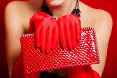 Mains femelles dans les gants rouges tenant un embrayage rouge image stock Mains femelles dans les gants rouges tenant un embrayage rouge image stock