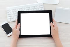 Mains femelles tenant un comprimé avec un écran d'isolement au-dessus d'un tabl image stock Mains femelles tenant un comprimé avec un écran d'isolement au-dessus d'un tabl image stock