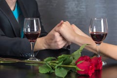 Mains modernes de couples sur la table de restaurant avec deux verres de vin rouge et de roses photo libre de droits Mains modernes de couples sur la table de restaurant avec deux verres de vin rouge et de roses photo libre de droits