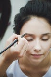 Make-up artist paints eyebrows to girl brunette, close-up royalty free stock photography Make-up artist paints eyebrows to girl brunette, close-up royalty free stock photography