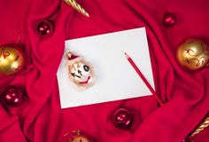 A clean white sheet of paper and a red pencil lie on the blanket, and next to them are red and gold Christmas balls. Creative