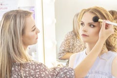 Makeupkonstnären applicerar modellerar makeup på framsida brud- makeup, ljust aftonsmink i näcka signaler arkivfoton Makeupkonstnären applicerar modellerar makeup på framsida brud- makeup, ljust aftonsmink i näcka signaler arkivfoton