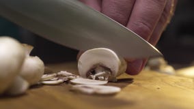 Makro- wideo kucharz pokrajać surowych szampiniony na drewnianej desce, gotuje pieczarki, jarski jedzenie, makro- jedzenie zdjęcie wideo Makro- wideo kucharz pokrajać surowych szampiniony na drewnianej desce, gotuje pieczarki, jarski jedzenie, makro- jedzenie zdjęcie wideo