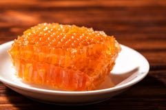 Makro-, zakończenie up Jaskrawi pomarańczowi honeycombs na śnieżnobiałym spodeczku brązowe drewniane tła kosmos kopii fotografia stock Makro-, zakończenie up Jaskrawi pomarańczowi honeycombs na śnieżnobiałym spodeczku brązowe drewniane tła kosmos kopii fotografia stock