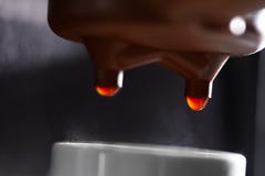 Makrofoto av att drypa kaffe i en kaffemaskinstekflott in i en kopp Processen av att göra en drink arkivfoto Makrofoto av att drypa kaffe i en kaffemaskinstekflott in i en kopp Processen av att göra en drink arkivfoto
