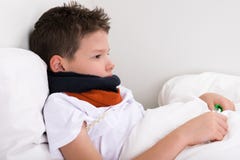 Malade de garçon dans le cou de lit rebobiné avec l'écharpe photos libres de droits Malade de garçon dans le cou de lit rebobiné avec l'écharpe photos libres de droits
