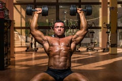 Male bodybuilder doing shoulder press whit dumbbell stock photos Male bodybuilder doing shoulder press whit dumbbell stock photos