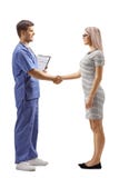 Male doctor in a blue uniform shaking hands with a young woman royalty free stock photos Male doctor in a blue uniform shaking hands with a young woman royalty free stock photos