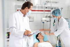 Male doctor holding medical form while nurse putting oxygen mask on patient royalty free stock photography Male doctor holding medical form while nurse putting oxygen mask on patient royalty free stock photography