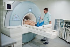 Male doctor turns on magnetic resonance imaging machine with patient inside