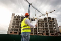 Male engineer in safety vest and hardhat looking at construction of new building stock images Male engineer in safety vest and hardhat looking at construction of new building stock images